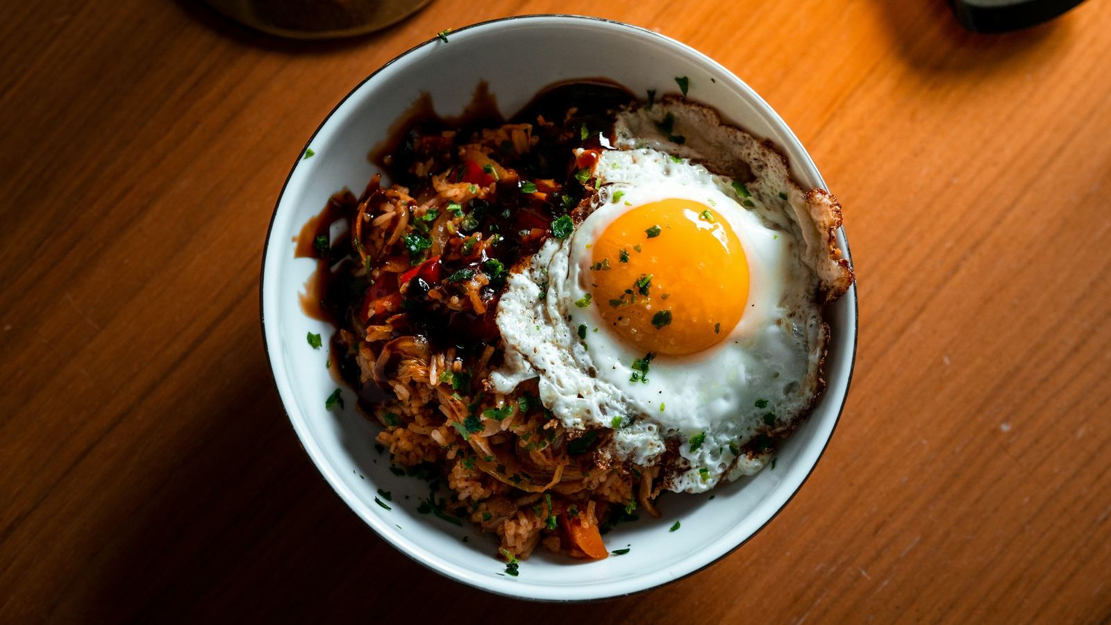A single bowl of dinner topped with a fried egg