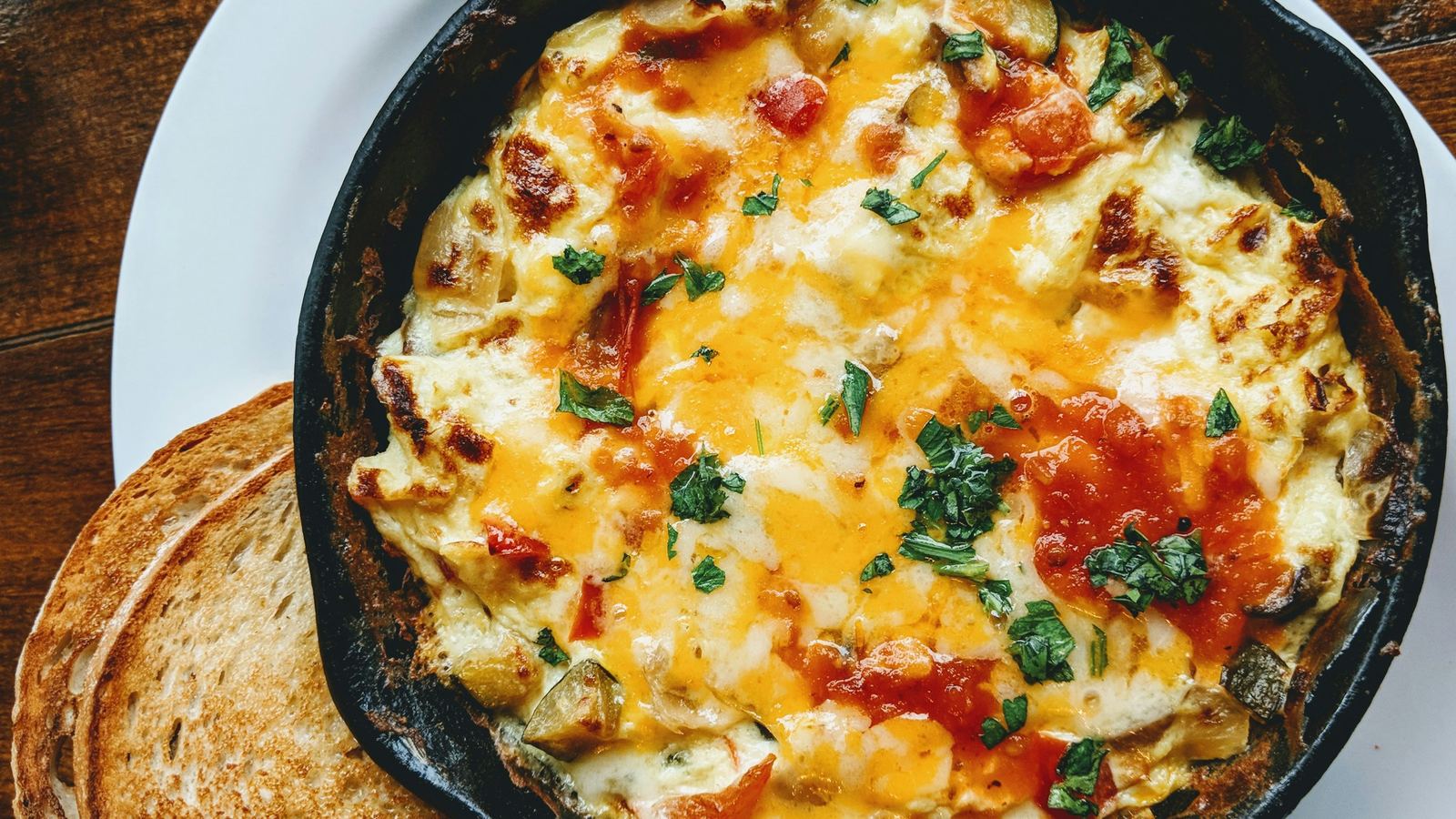 Baked eggs with cheese and tomato in a cast-iron pan, with toast