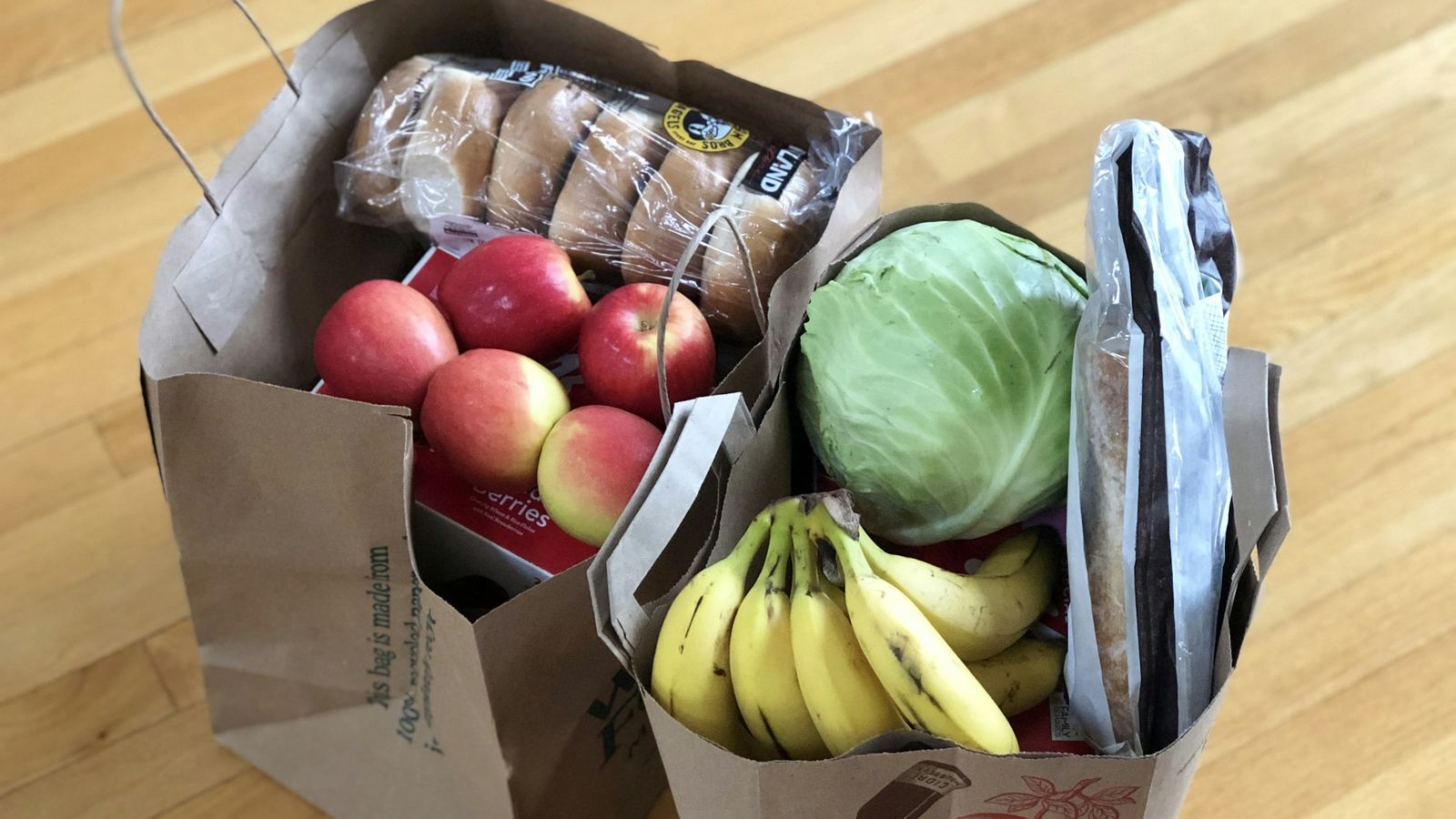 Paper shopping bags with apples, bananas, bread and a cabbage